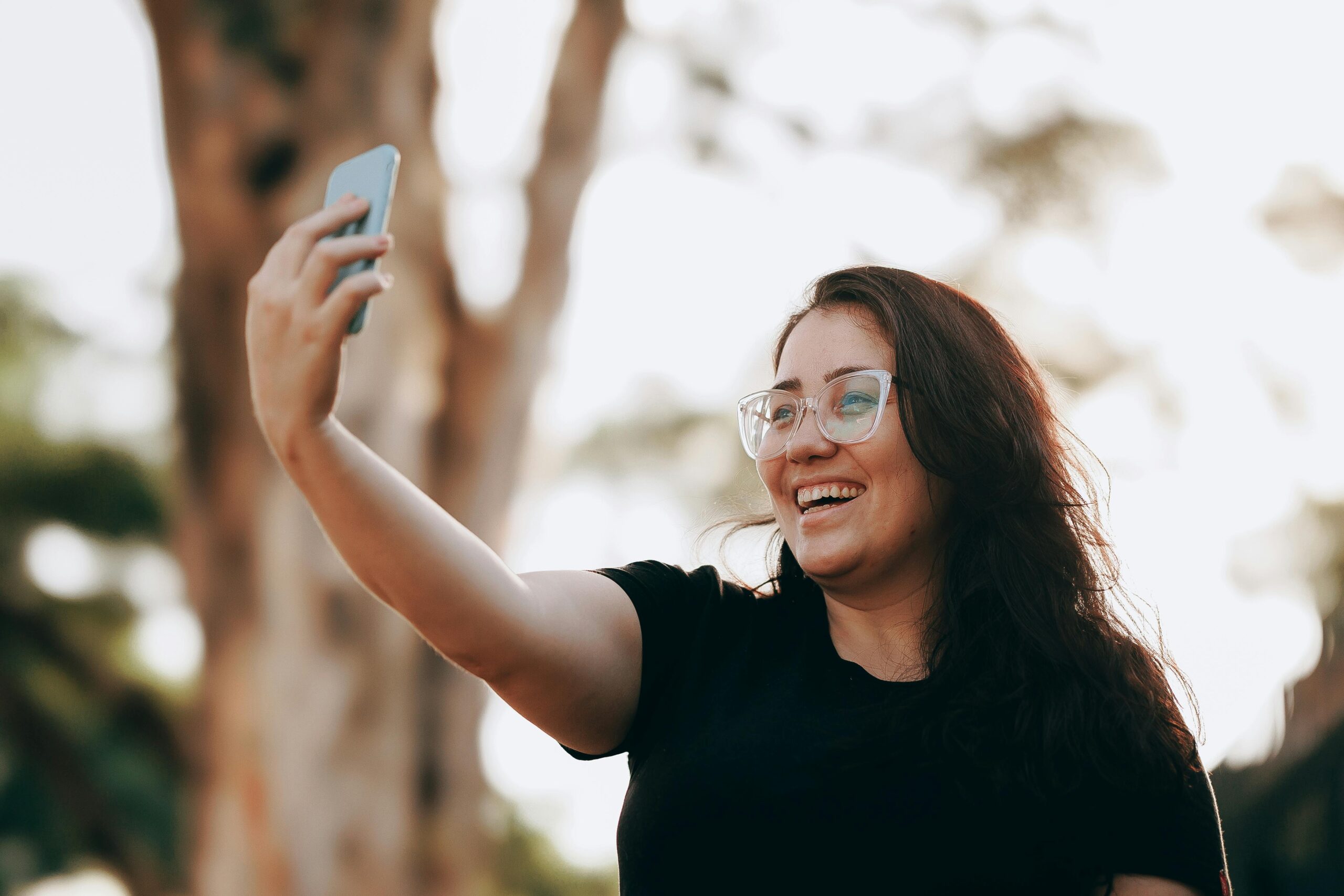 a woman smiling while livestreaming on a smartphone