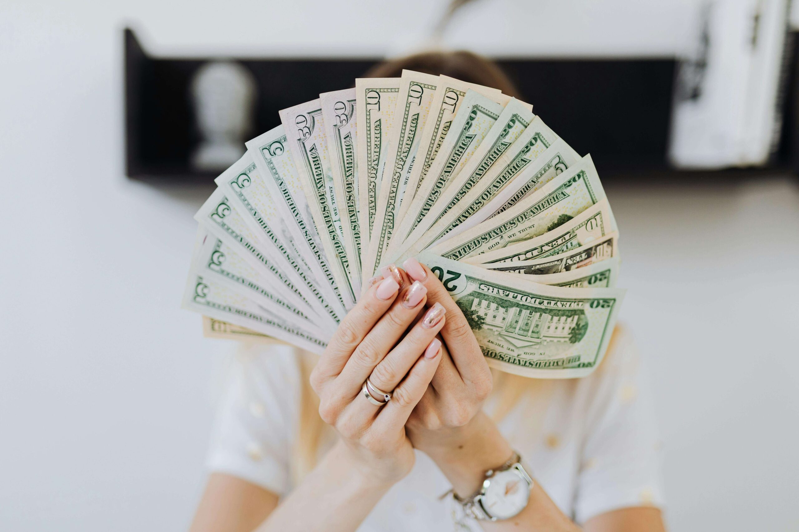 a woman holding up a fan of bank notes