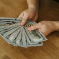 a man holding several hundred dollar bills
