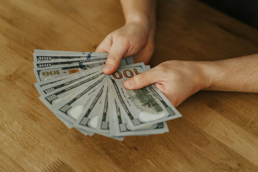 a man holding several hundred dollar bills