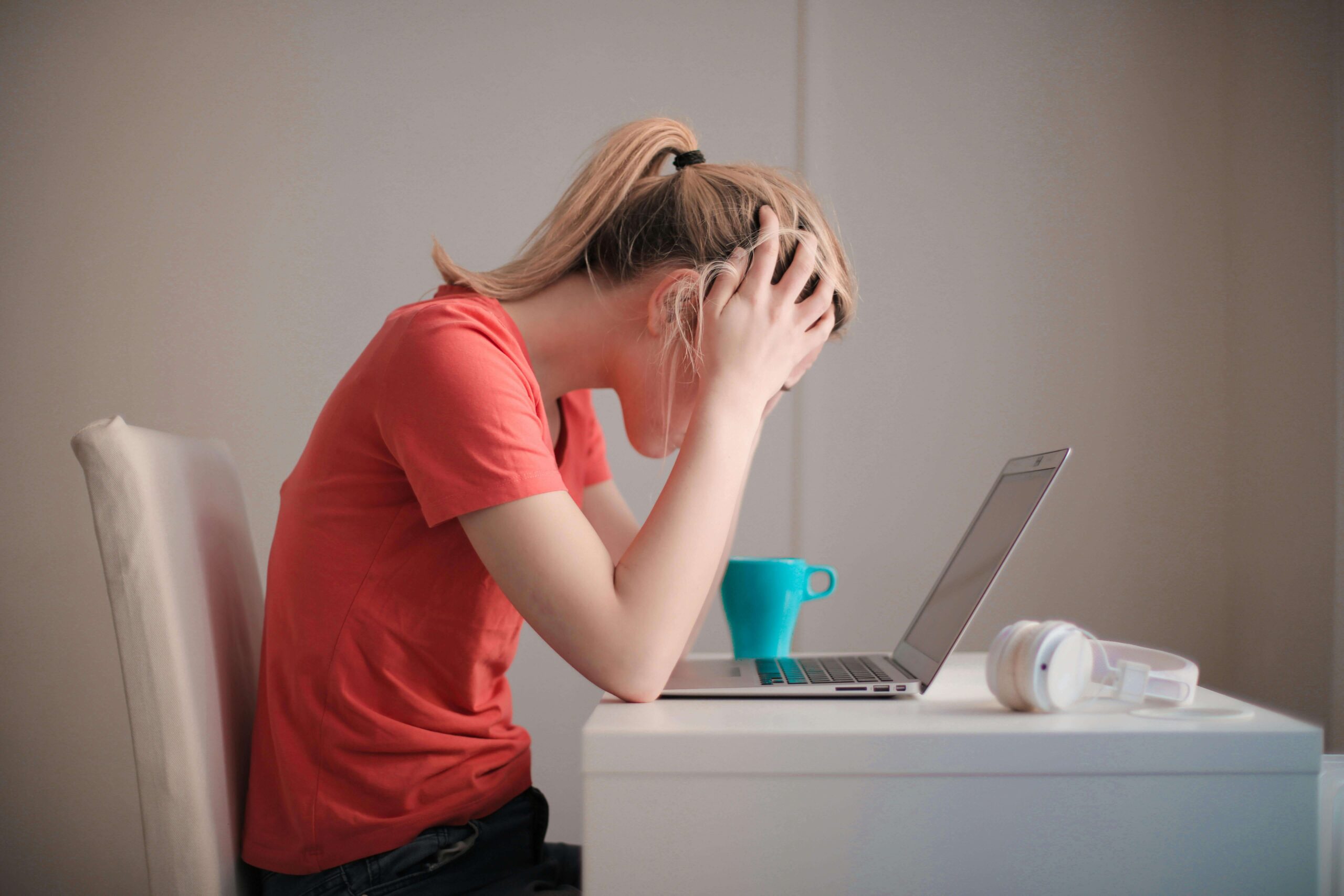a woman with a head in her hands looking at a computer screen