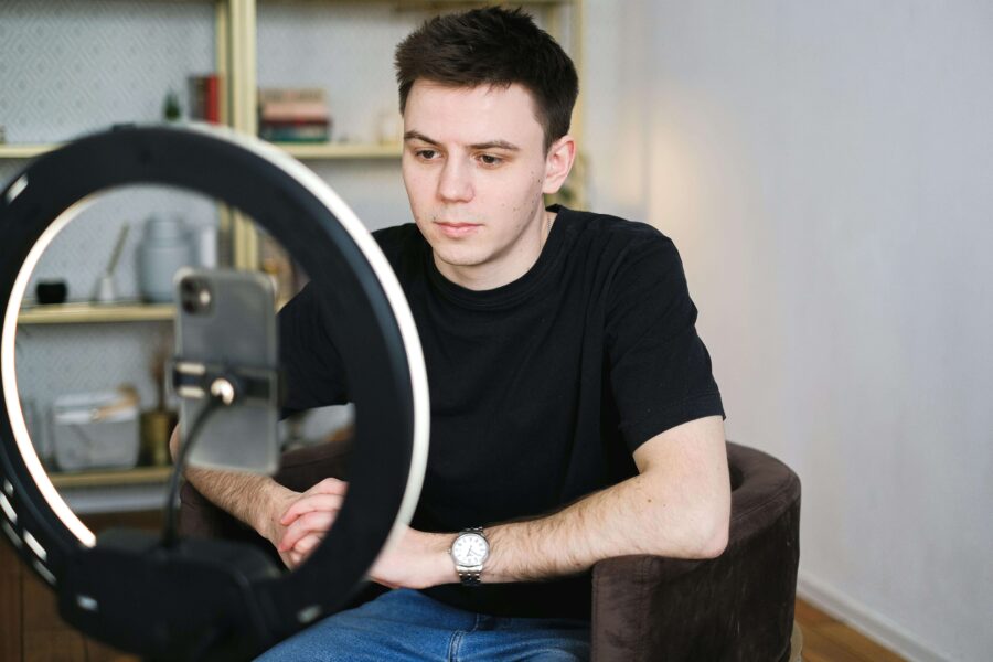 a male cam model in front of a ring light and smartphone